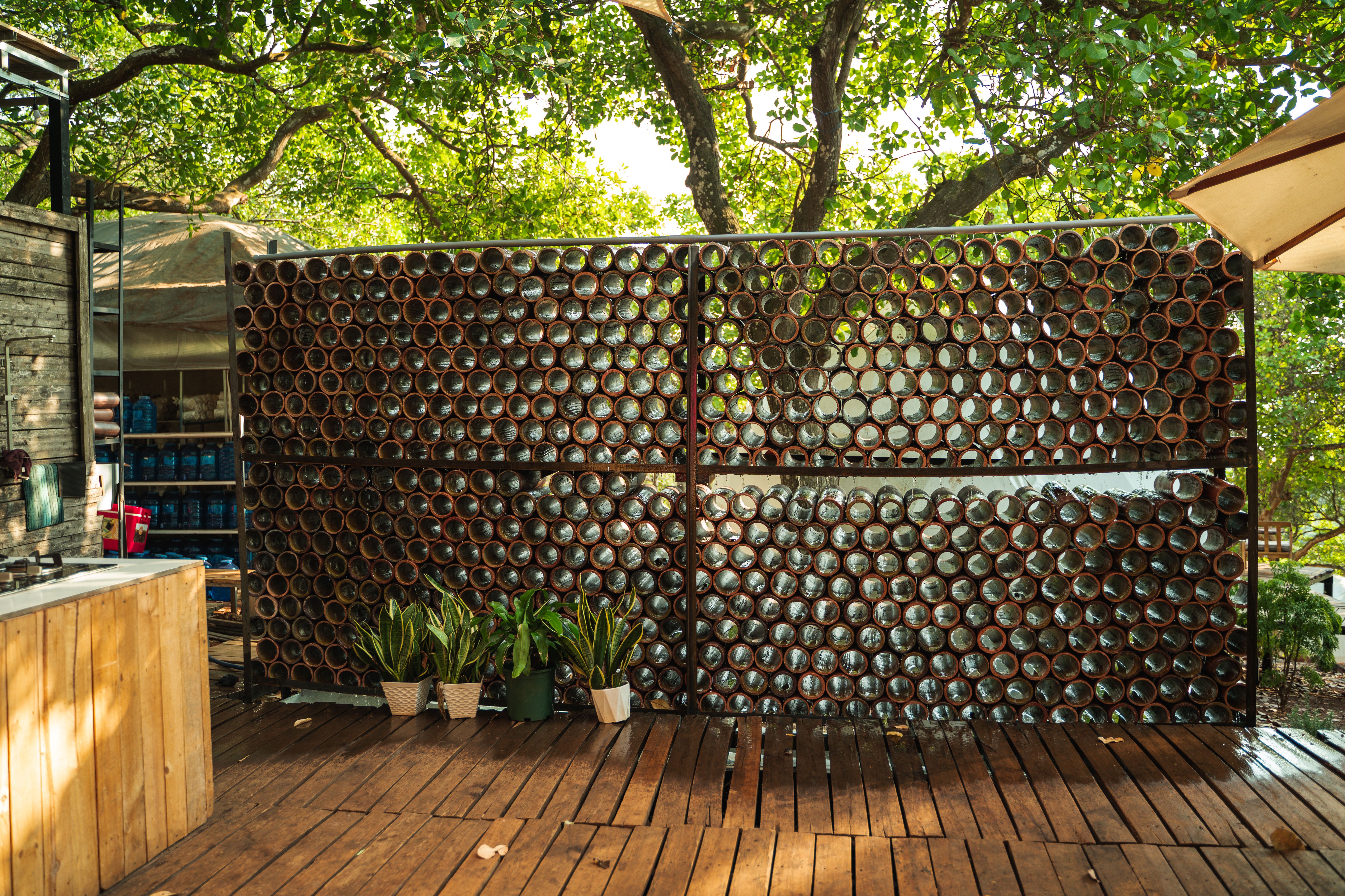 Outdoor garden wall made of glass bottles surrounded by trees